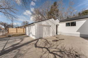 Detached garage featuring concrete driveway and fence