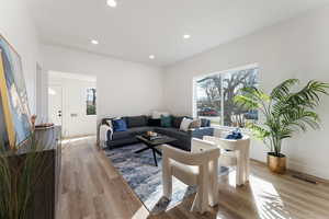 Living room featuring light wood-type flooring, visible vents, baseboards, and recessed lighting