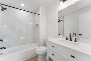 Full bathroom featuring bathing tub / shower combination, toilet, wood finished floors, vanity, and recessed lighting