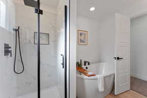 Primary en suite bathroom featuring tub and shower.