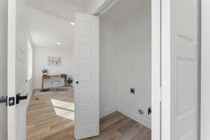 Washroom with baseboards, laundry area, light wood-style flooring, and hookup for an electric dryer