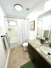 Bathroom with shower / tub combo, visible vents, toilet, tile patterned flooring, and vanity