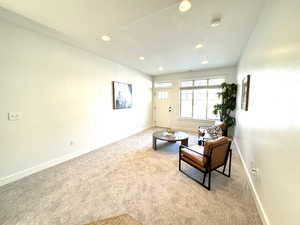 Living area with light carpet, recessed lighting, and baseboards