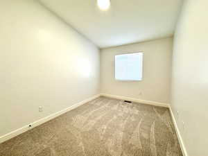 Spare room with carpet, visible vents, and baseboards