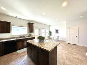 Kitchen featuring a kitchen island, a sink, visible vents, light stone countertops, and dishwasher