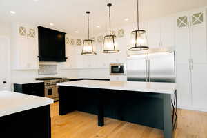 Kitchen featuring built in appliances, hanging light fixtures, light countertops, and a center island