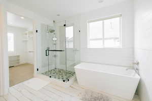 Full bathroom featuring a stall shower, tile walls, and a freestanding bath