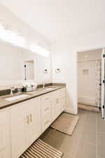 Full bathroom featuring shower / bath combination, double vanity, and tile patterned floors