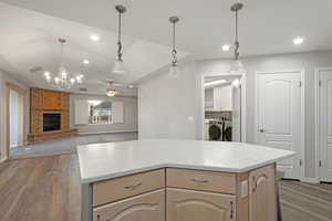 Kitchen featuring hardwood / wood-style flooring, washing machine and dryer, a center island, and light brown cabinets