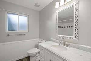 Bathroom with hardwood / wood-style flooring, vanity, and toilet