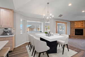 Dining room with dark wood-type flooring, a fireplace, and an inviting chandelier