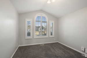 Unfurnished room featuring vaulted ceiling and carpet flooring