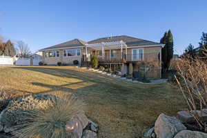 Back of property featuring a wooden deck, a lawn, and a pergola