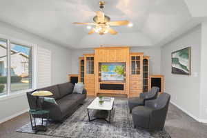 Carpeted living room with ceiling fan, lofted ceiling, and plenty of natural light