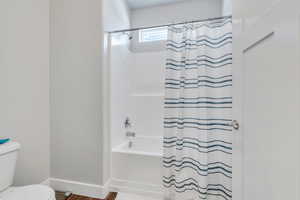 Full Master bathroom with shower / tub combo, baseboards, toilet, and wood finished floors