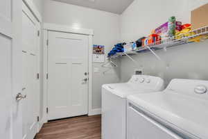 Laundry room featuring dark wood-style floors, laundry area, and washing machine and clothes dryer