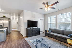 Living room with a textured ceiling, visible vents, and a ceiling fan