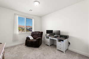 Office space with baseboards, visible vents, and light colored carpet