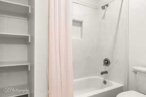 Bathroom with toilet and shower / bath combo with shower curtain