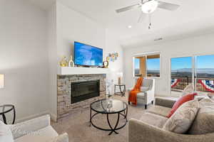 Living room with ceiling fan, carpet floors, a fireplace, visible vents, and baseboards