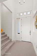 Foyer entrance featuring stairs, carpet flooring, and baseboards