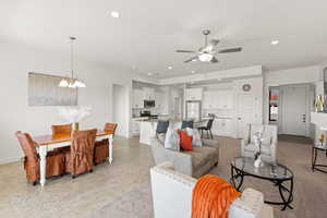 Living area with ceiling fan with notable chandelier, baseboards, and recessed lighting