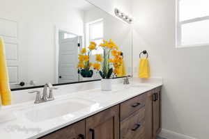 Full bath featuring double vanity, baseboards, and a sink