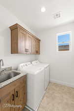 Laundry room with washer and clothes dryer, cabinet space, visible vents, a sink, and baseboards