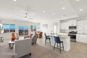 Kitchen featuring appliances with stainless steel finishes, a kitchen breakfast bar, light stone countertops, a kitchen island with sink, and a sink