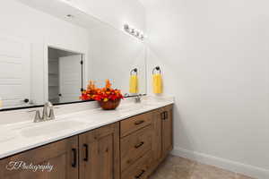 Full bathroom featuring double vanity, tile patterned flooring, a sink, and baseboards