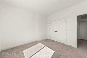 Unfurnished bedroom featuring carpet floors, a closet, visible vents, and baseboards