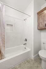 Full bathroom with baseboards, shower / bath combo, toilet, and tile patterned floors