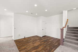 Empty room featuring recessed lighting, wood finished floors, visible vents, baseboards, and stairway