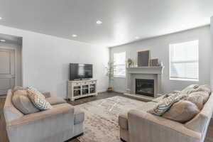 Living area featuring baseboards, a glass covered fireplace, wood finished floors, and recessed lighting