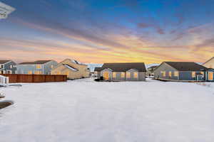 Snow covered back of property with a residential view, fence, and an outdoor structure