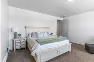 Bedroom with dark carpet and baseboards