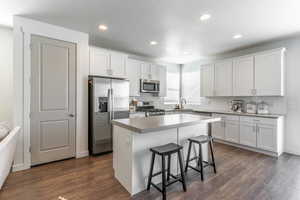 Kitchen featuring dark wood-style floors, white cabinetry, stainless steel appliances, and a sink