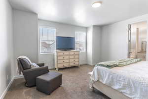 Carpeted bedroom with connected bathroom, a textured ceiling, and baseboards