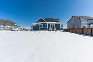 Snow covered property featuring a residential view and fence