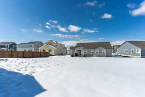 Snowy yard featuring a residential view and fence