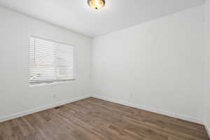 Unfurnished room featuring wood finished floors, visible vents, and baseboards