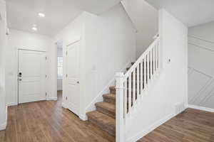 Staircase with baseboards, wood finished floors, and recessed lighting