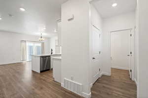 Corridor featuring baseboards, visible vents, dark wood finished floors, a sink, and recessed lighting