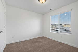 Spare room with carpet flooring, visible vents, and baseboards