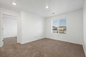 Carpeted empty room with visible vents, baseboards, and recessed lighting