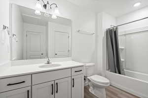 Bathroom with shower / bath combo with shower curtain, vanity, toilet, and wood finished floors