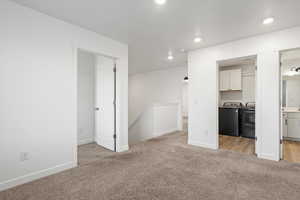 Unfurnished living room with light carpet, baseboards, washing machine and clothes dryer, and recessed lighting