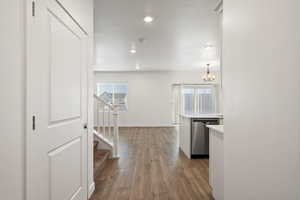 Corridor featuring baseboards, dark wood-style floors, an inviting chandelier, stairs, and recessed lighting