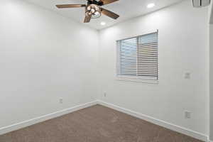 Spare room with dark colored carpet, ceiling fan, baseboards, and recessed lighting