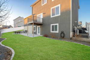 Back of house with a patio, a balcony, fence, a yard, and stucco siding